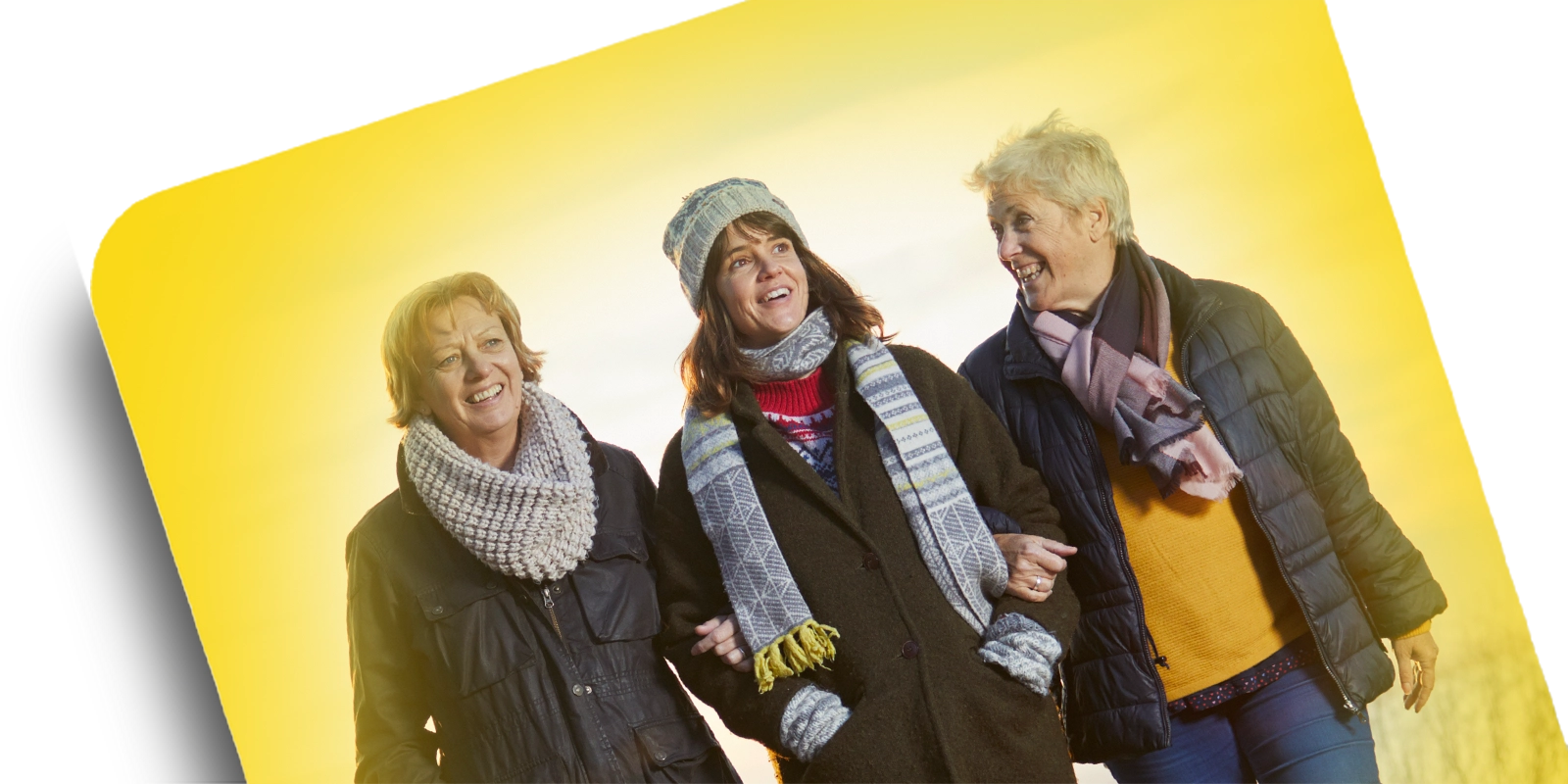 Three women smiling with arms linked